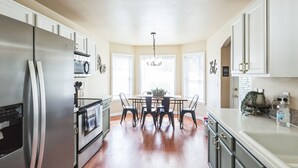 Una cocina moderna con un refrigerador de acero inoxidable, horno empotrado y una mesa de comedor con sillas.