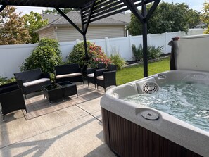 A hot tub in a backyard with patio furniture and a white fence. - Cozy Corner Oasis With Hot Tub 4 Bedroom Home (Twin Falls)