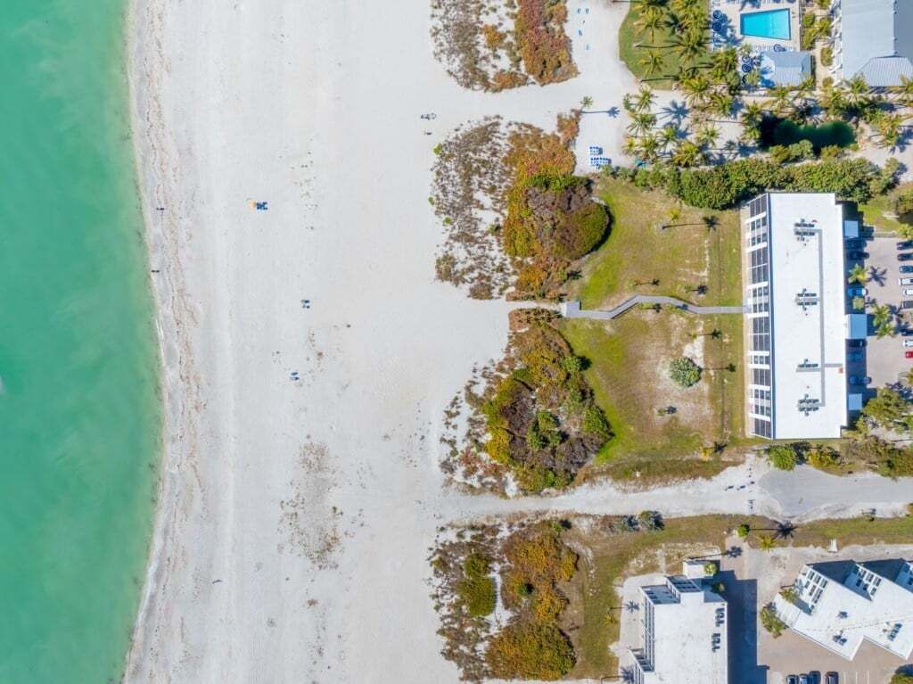 Eine Luftaufnahme einer Küstenlandschaft mit Strand, Schwimmbad und einem Gebäude im modernen Stil.