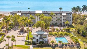 A hotel with a pool, palm trees, and a view of the ocean.