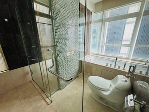 A modern bathroom with a glass shower enclosure, a toilet, and a bathtub. - The Binjai Presidential Suite (Kuala Lumpur)