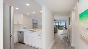A modern kitchen with white cabinets, a dishwasher, and a view to the outside. - Pelicans Roost 104 2 Bedroom Condo (Sanibel)