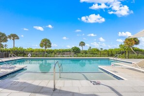 Un cielo azul despejado con una piscina rodeada de una cerca y palmeras.