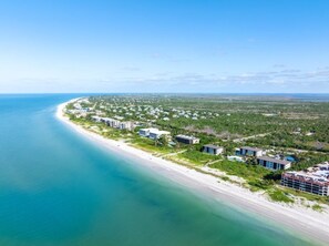 An aerial view of a coastal area with a beach, buildings, and greenery. - Tarpon Beach 302 3 Bedroom Condo (Sanibel)