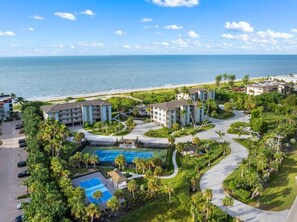 Un resort con varias construcciones, un área de piscina y vista al mar.
