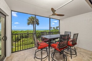 A balcony with a table and chairs, a ceiling fan, and a view of the ocean. - Tarpon Beach 302 3 Bedroom Condo (Sanibel)