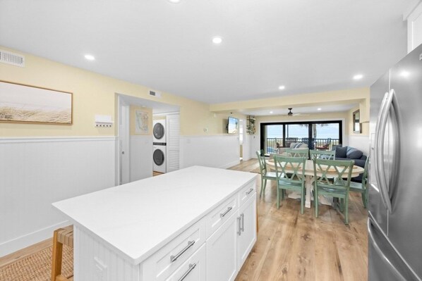 Een moderne keuken met witte kasten, een centraal eiland en een eethoek met groene stoelen.