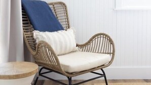A wicker chair with a cushion, a small round table with a woven top, and a framed painting on the wall. - Tarpon Beach Unit 110 2 Bedroom Condo (Sanibel)