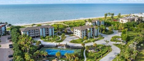 A resort with multiple buildings, a pool area, and a beach view.