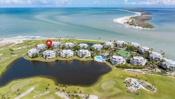 An aerial view of a resort with multiple buildings, a golf course, and a large body of water. - Captivated By The Sea 2 Bedroom Condo (Captiva)