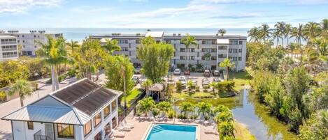 A resort with a swimming pool, palm trees, and a view of the ocean.