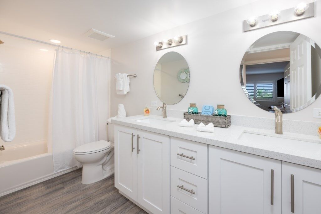 Une salle de bain moderne avec un meuble-lavabo blanc, un grand miroir et une baignoire.