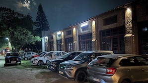 A parking area with several cars parked in front of a building with brick walls and multiple windows.