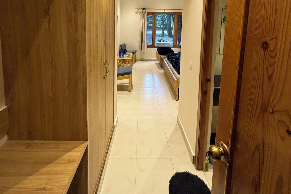 Un pasillo con armarios de madera, un banco y una puerta que da a una habitación con ventana.