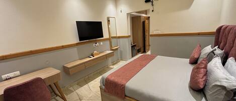 Une chambre d’hôtel équipée d’un lit, d’un bureau, d’une chaise, d’une télévision et d’un appareil de climatisation.