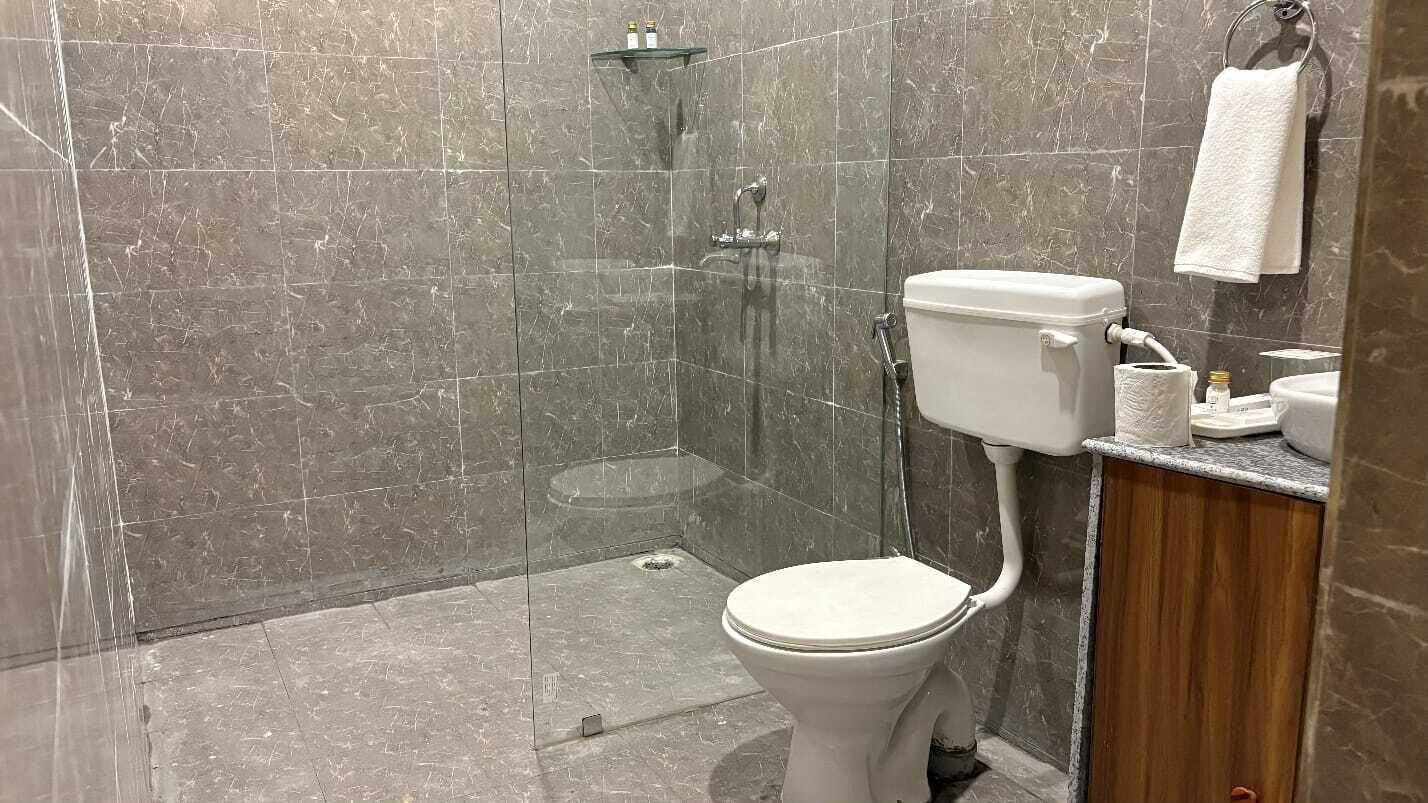 Un baño con ducha, inodoro y lavamanos, con un perchero para toallas.