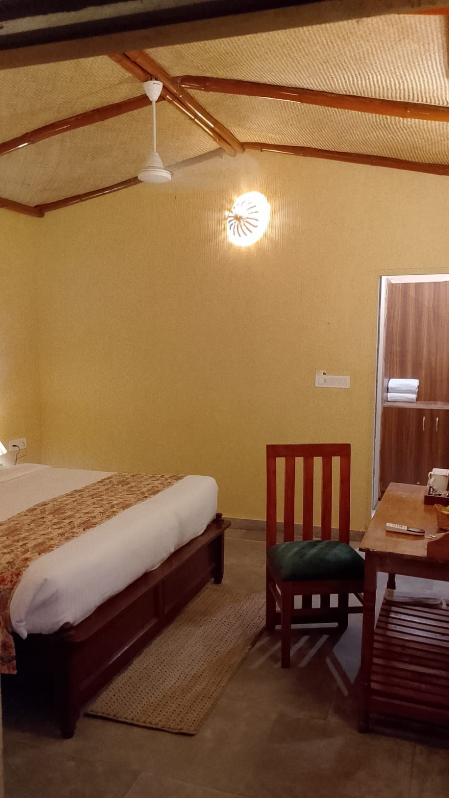 Una habitación con cama, una silla, una mesa y un ventilador de techo.