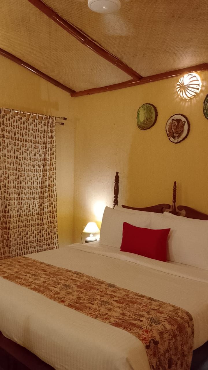 A hotel room with a bed, a headboard, a wall clock, and a wall-mounted light fixture.