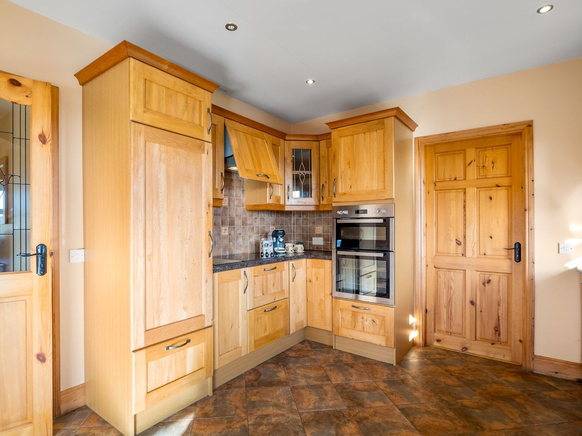 A kitchen with wooden cabinets, a double oven, and a tiled backsplash.