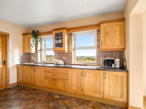 A kitchen with wooden cabinets, a window with a view, and a microwave on the counter.