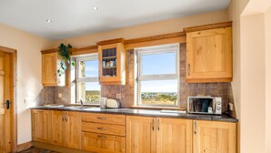 A kitchen with wooden cabinets, a window with a view, and a microwave on the counter.
