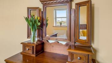 A wooden dresser with a mirror and a vase of flowers.