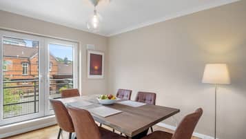A dining area with a wooden table, six chairs, a bowl of fruit, and a floor lamp.