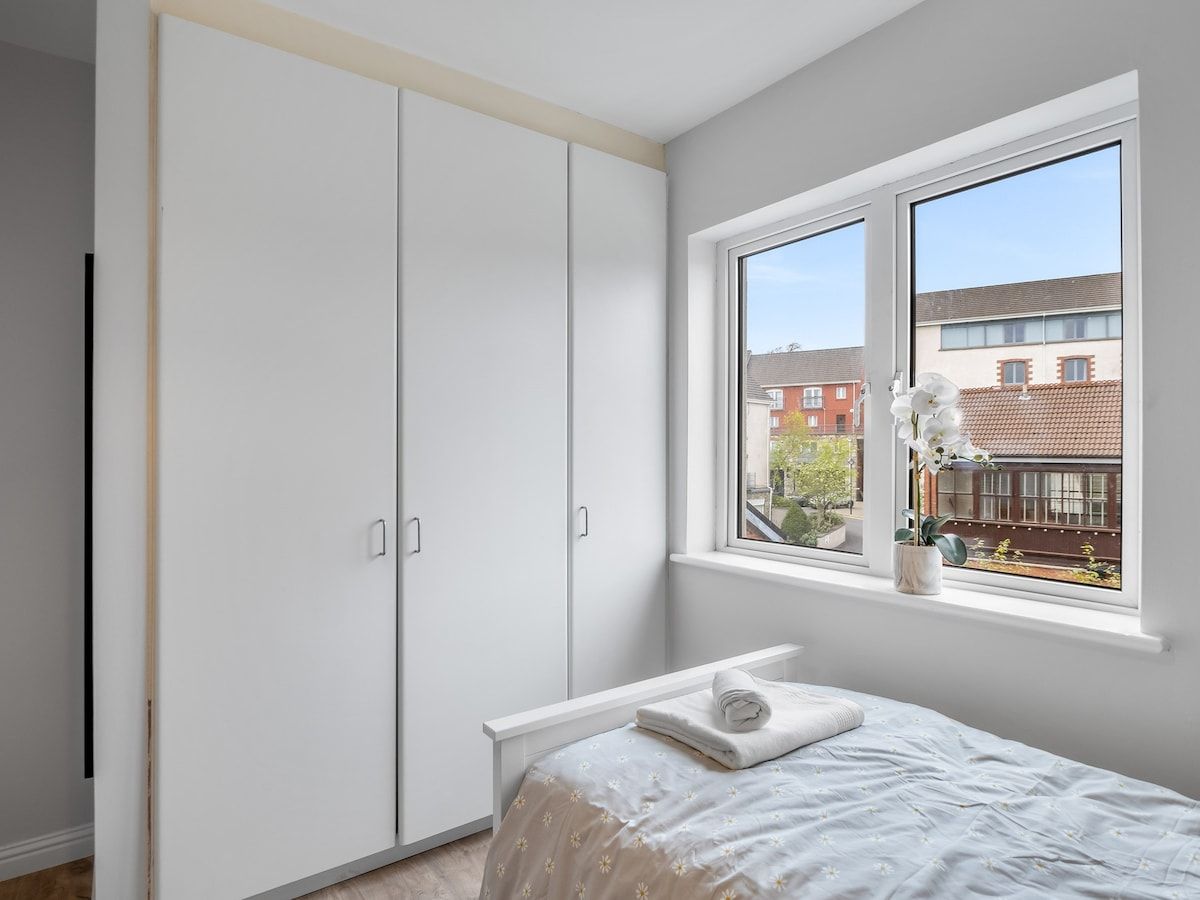 A bedroom with a bed, a window, and a wardrobe.