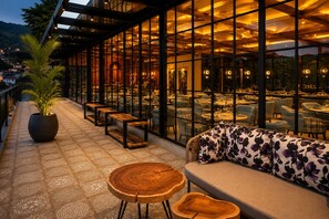 Un espacio al aire libre con mesas, bancos, una planta en maceta y un sofá con cojines estampados.