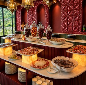A buffet with various food items and a scenic view through the windows.