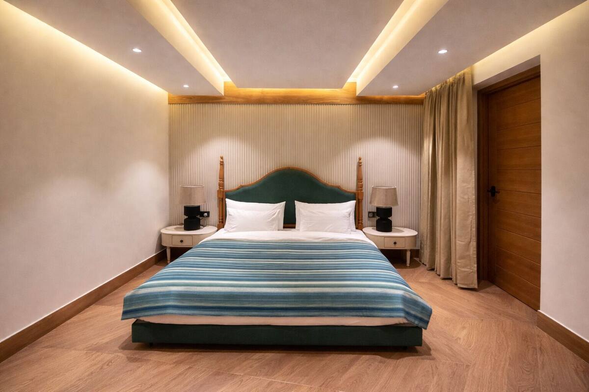 Una camera d'albergo con un letto grande, due comodini, una testiera in legno e una porta di legno.