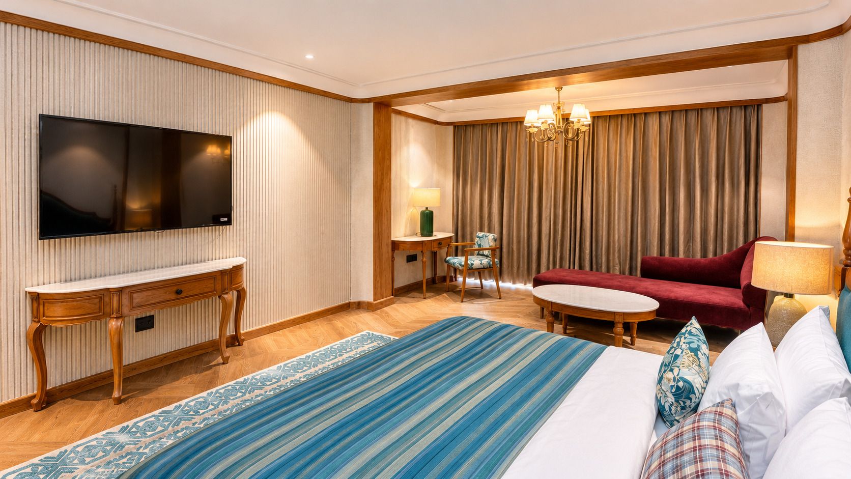 Une chambre d’hôtel avec un lit, une télévision, un canapé rouge, une petite table et une lampe.