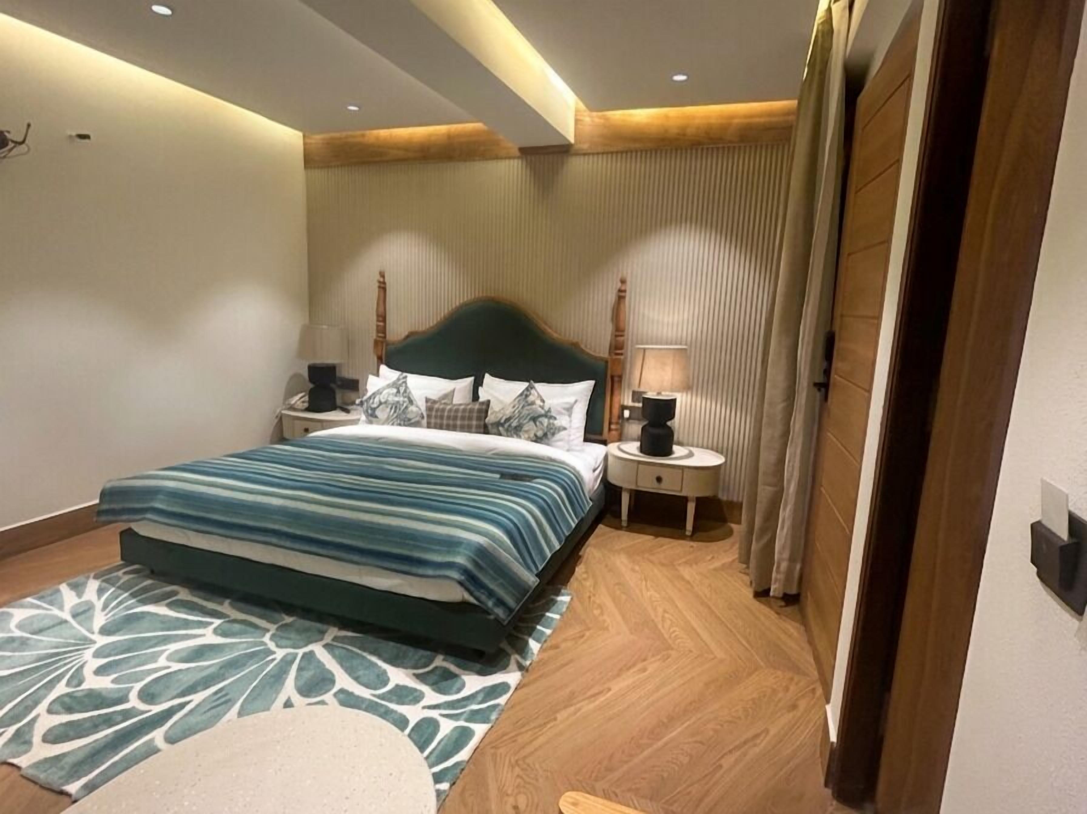 A hotel room with a bed, nightstands, and a wooden floor.