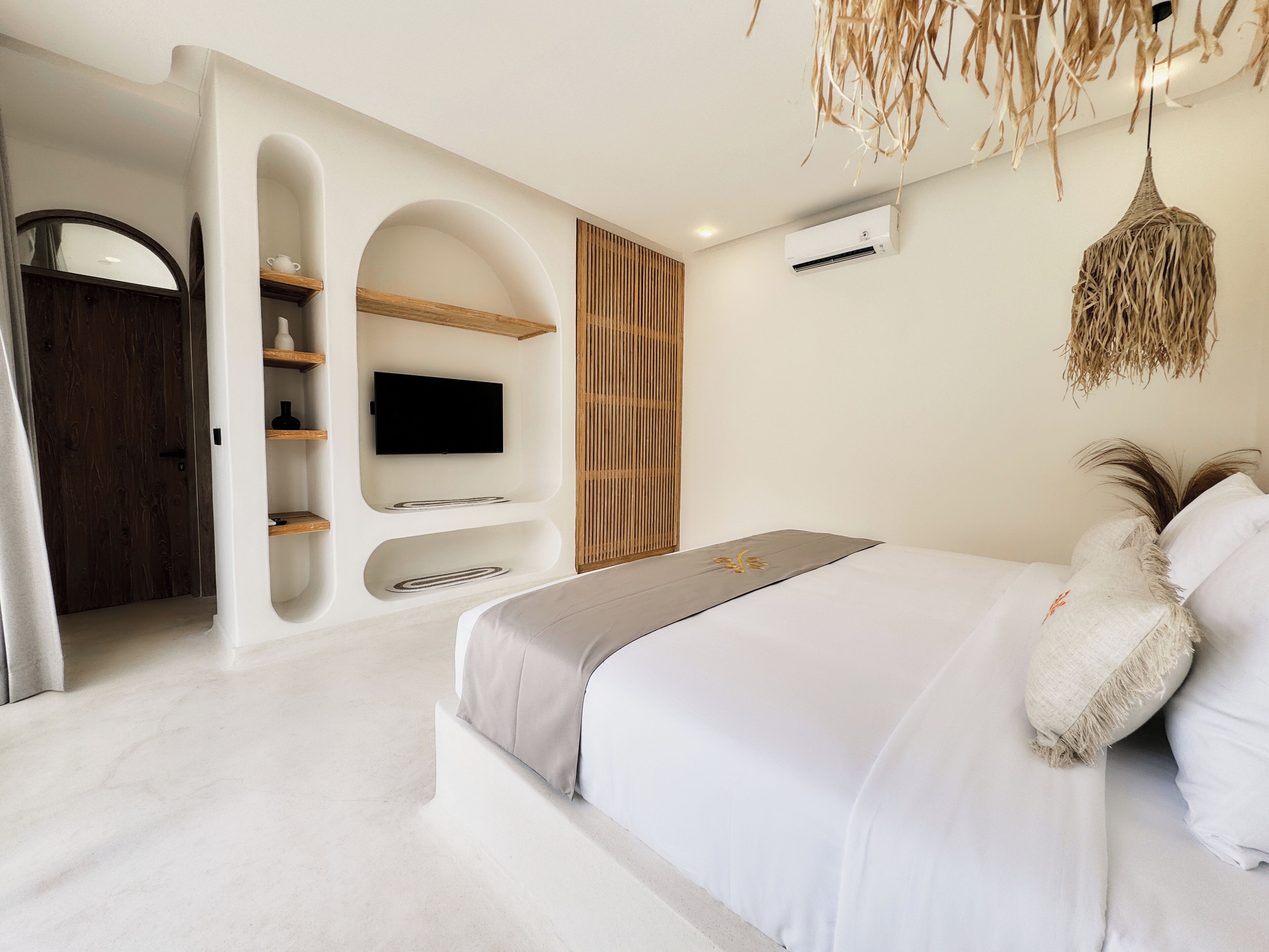 A modern bedroom with a large bed, built-in shelves, a flat-screen TV, and a ceiling fan.
