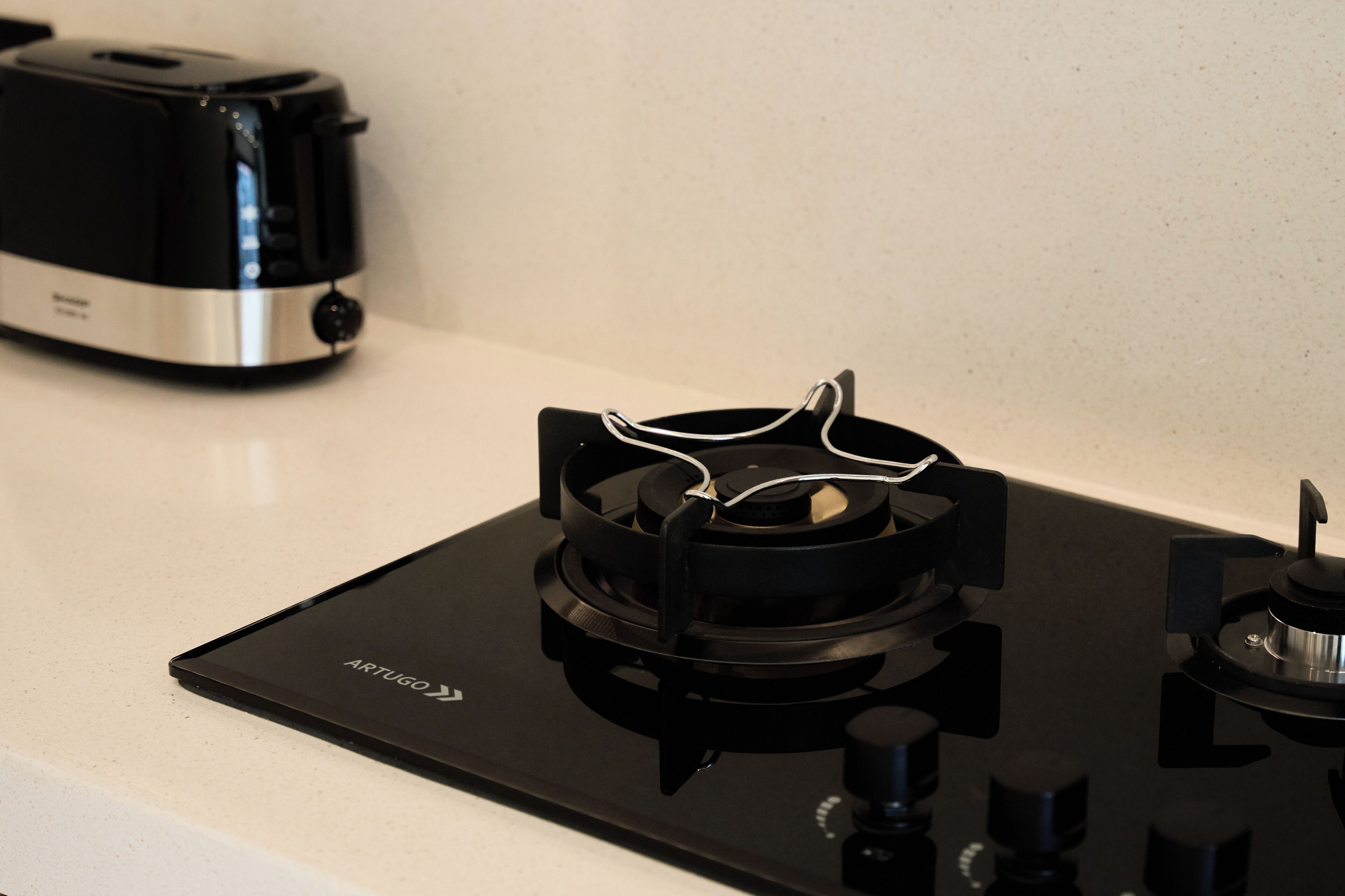 A kitchen with a black induction cooktop and a coffee maker on the counter.