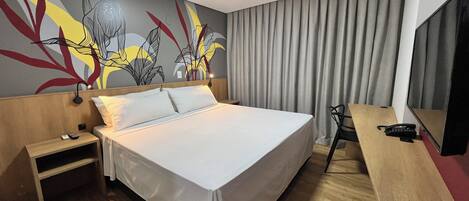 Una habitación de hotel moderna con una cama grande, un escritorio y un mural en la pared.