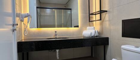 Un baño moderno con encimera negra, un lavamanos, un inodoro y un perchero para toallas.