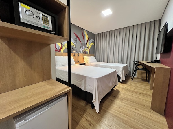 A hotel room with two beds, a desk, a television, and a minibar.