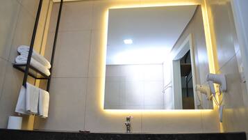 A modern bathroom with a large mirror, a towel rack, a hairdryer, and a sink.