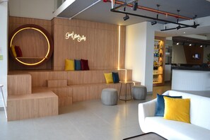 A modern lounge area with a wooden wall, a neon sign, and a bar in the background.