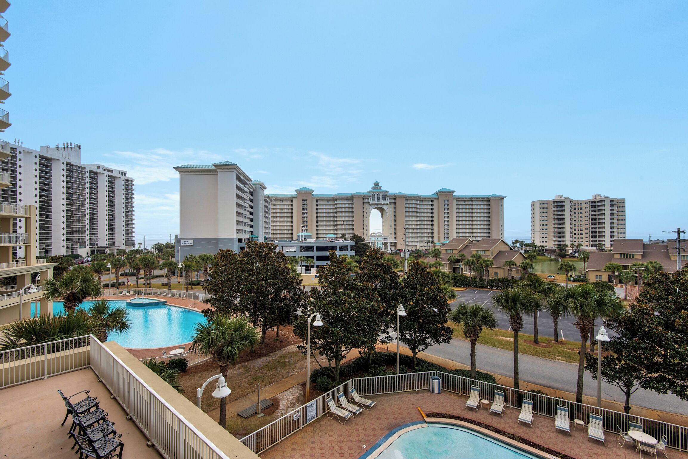 Un hotel con una piscina grande, varios balcones y vistas de los edificios circundantes.