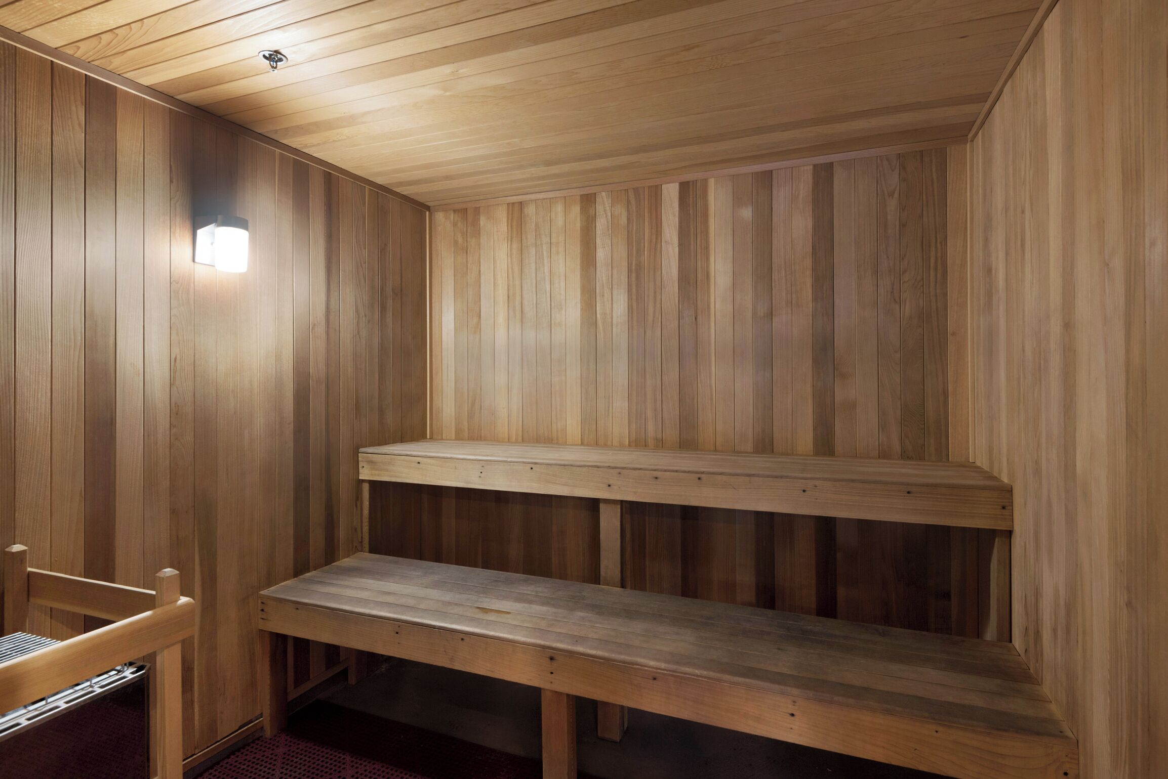 Una sauna de madera con bancos y una lámpara.
