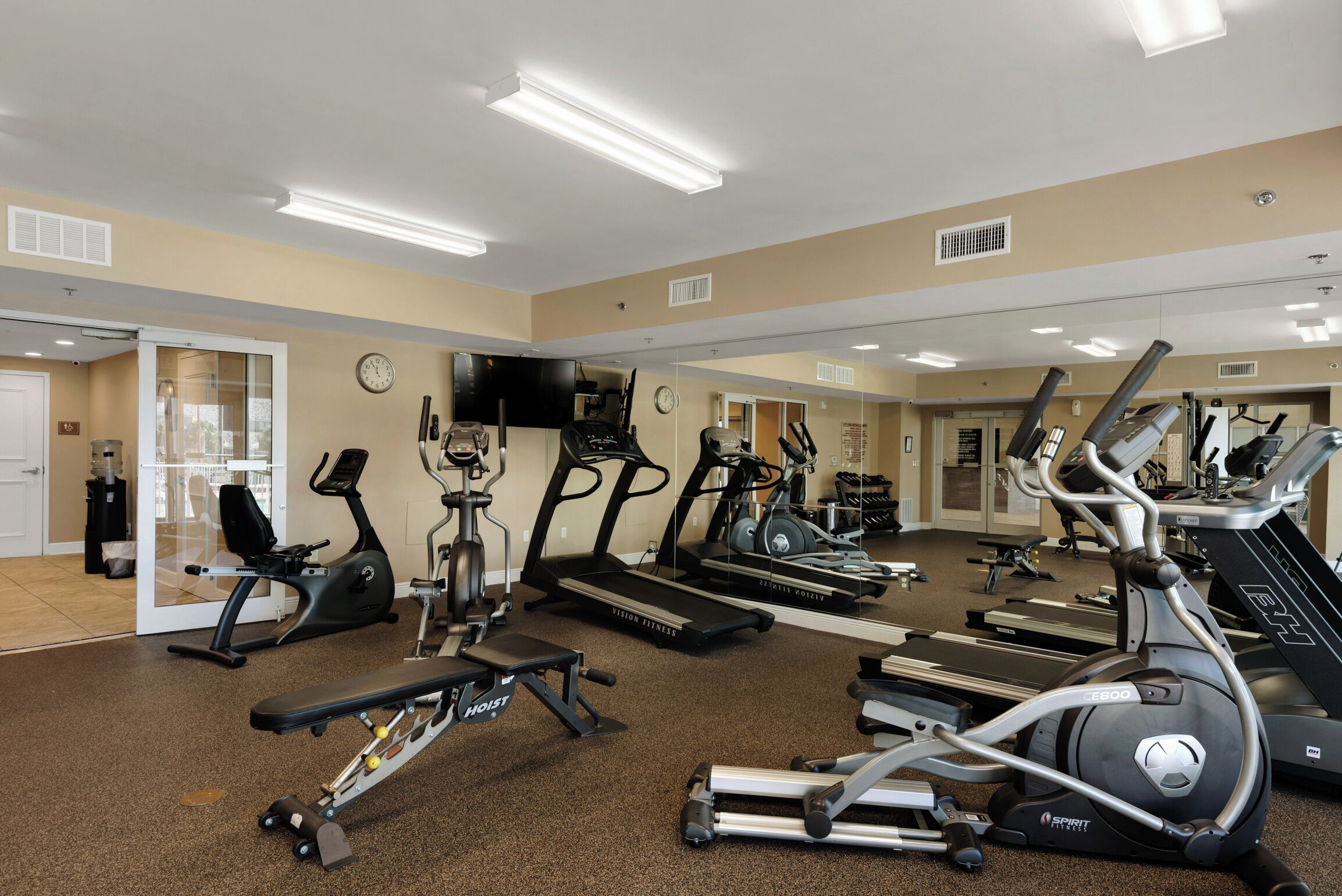 A gym with treadmills, elliptical machines, and a bench press.