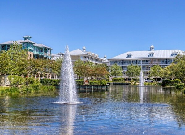 A fountain in a park with buildings in the background.