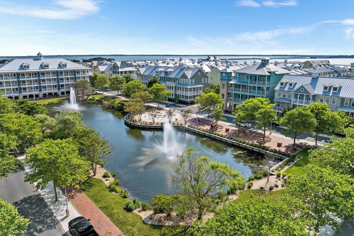 A waterfront hotel with multiple buildings, a central fountain, and a well-maintained garden area.