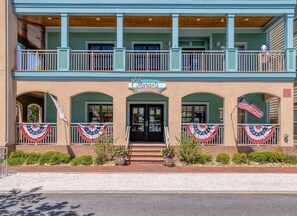 Un edificio di due piani con un balcone, un'insegna che recita 'Marie's Market & Cafe' e bandiere americane.