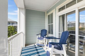 A balcony with two Adirondack chairs and a striped rug.