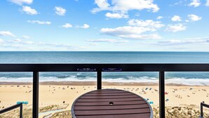 Blick auf den Strand vom Balkon, mit Pooltisch, Sandstrand und dem Meer.