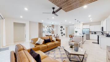 Un salon moderne avec un canapé en cuir marron, une table basse et un ventilateur de plafond.