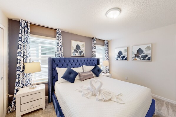 Une chambre à coucher bien rangée, avec un grand lit, une table de chevet et une commode.